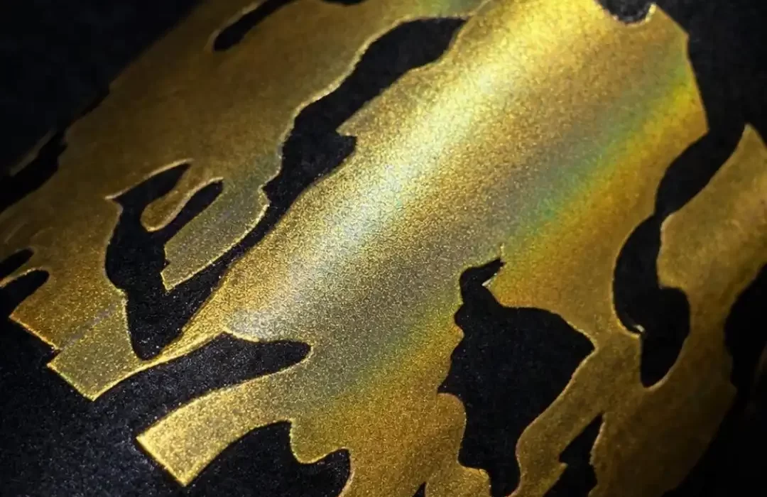Close-up of a black fabric featuring a gold metallic foil DTF print, showing a smooth, reflective finish that fully covers the artwork with a premium shine.